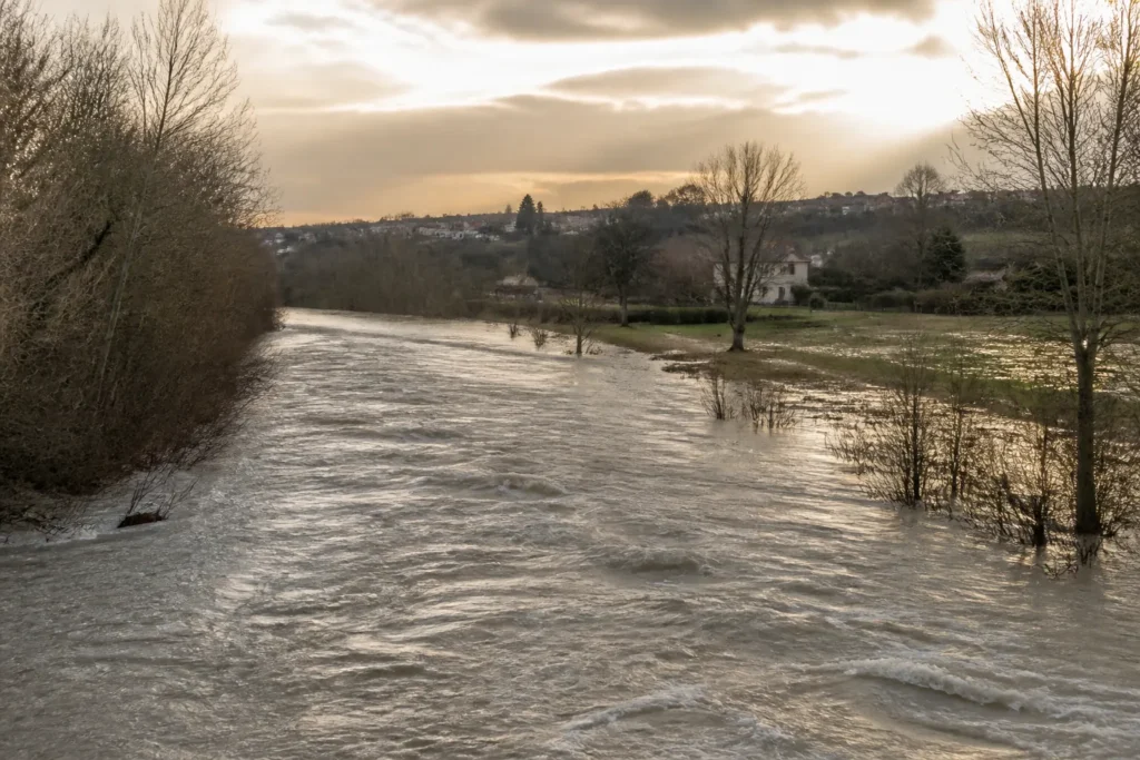 Riviere en crue dans une plaine avec habitations au loin